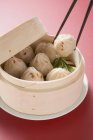 Closeup view of Dim Sum in bamboo steamer with chopsticks holding one — Stock Photo