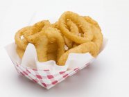 Deep-fried onion rings in paper dish — Stock Photo