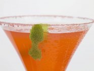 Вид крупным планом клубничного напитка в стакане с сахарным ободом и лаймовой кожурой — стоковое фото