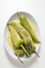 Chiles asados en plato blanco sobre fondo blanco - foto de stock