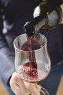 Pessoa derramando vinho tinto em um copo — Fotografia de Stock