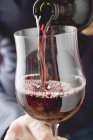Person gießt Rotwein in ein Glas — Stockfoto