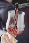 Person gießt Rotwein in ein Glas — Stockfoto