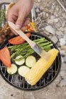 Closeup view of hand brushing corn cob on barbecue with oil — Stock Photo