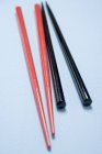 Closeup view of red and black chopsticks on light-blue surface — Stock Photo