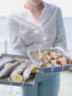 Frau hält Tabletts mit Fisch und Dönerspießen — Stockfoto