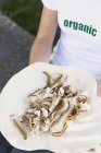 Vista elevata della donna che tiene piatto di funghi tagliati a fette — Foto stock