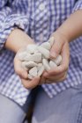 Closeup view of child holding a handful of pebbles — Stock Photo