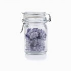 Closeup view of sweets in glass preserving jar on white background — Stock Photo