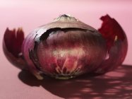 Красный лук на розовом фоне — стоковое фото