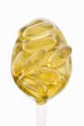 Closeup view of yellow fish fat capsules on a spoon — Stock Photo