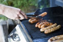 Man cooking Sausages on barbecue — Stock Photo