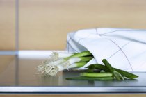 Spring onions wrapped in a tea towel — Stock Photo