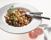 Перець і помідор салат з креветками на білій тарілці з виделкою і ножем — стокове фото