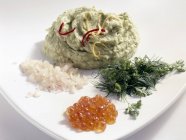 Puré de aguacate con hierbas, chalotes y caviar de trucha en plato blanco - foto de stock