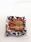 Red mullet with vegetables and herbs on aluminium foil over white surface — Stock Photo