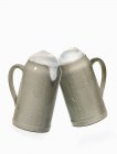 Mugs of beer clinking together — Stock Photo