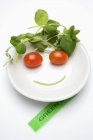 Gemüsegesicht in Suppenteller, Etikett daneben auf weißem Hintergrund — Stockfoto