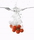 Tomates cereja caindo na água — Fotografia de Stock