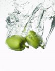 Peppers falling into water — Stock Photo