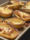 Baked potato skins with bacon in baking dish — Stock Photo