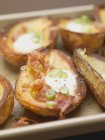 Pelli di patate al forno con pancetta, panna acida e anelli di peperoncino in piatto bianco — Foto stock