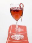 Closeup view of cranberry drink with candy cane in glass — Stock Photo