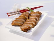 Closeup view of sliced duck breast on plate with chopsticks — Stock Photo