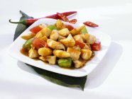 Vista de cerca de pollo Kung Pao con verduras en plato blanco y hoja - foto de stock