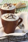 Hot chocolate in cups with cream topping — Stock Photo