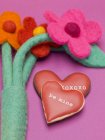 Nahaufnahme herzförmiger Kekse mit rotem Zuckerguss und Filzblumen — Stockfoto
