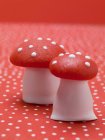 Closeup view of marzipan fly agaric mushrooms on red dotted surface — Stock Photo