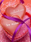 Vista de cerca de los corazones de vainilla con glaseado rojo y escritos para el Día de San Valentín - foto de stock