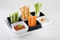 Tray of vegetable sticks, savoury straws and dips  on white background — Stock Photo
