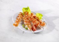 Elevated view of prawn skewers on lettuce leaves — Stock Photo
