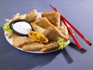 Elevated view of Samosas with dip, vegetables and chopsticks on plate — Stock Photo