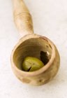 Olive in wooden ladle over white surface — Stock Photo