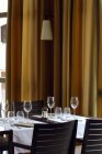 Gedeckter Tisch in einem Restaurant mit Vorhängen vor dem Hintergrund — Stockfoto
