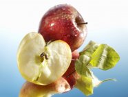 Manzana entera y cortada a la mitad con hojas - foto de stock
