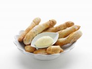 Breadsticks with butter in bowl — Stock Photo