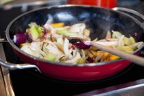 Vue rapprochée des légumes dans une casserole avec une cuillère en bois — Photo de stock