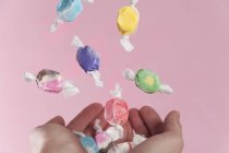 Cropped view of hands catching falling sweets — Stock Photo