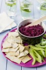 Beetroot dip with crisps and celery in bowl over plate — Stock Photo
