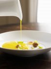 Glatte und cremige Kürbissuppe in eine weiße Schüssel mit Garnierungen gießen — Stockfoto