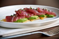 Raw tuna slices over sliced avocado — Stock Photo