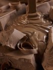 Растаянный шоколад льется на куски — стоковое фото