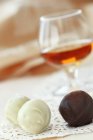 Nahaufnahme von weißen und dunklen Schokoladentrüffeln mit Weinglas auf Hintergrund — Stockfoto