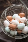 Elevated view of white and brown hen eggs in a wire basket — Stock Photo
