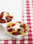 Summer fruit salad with cream in glass bowls over towel — Stock Photo