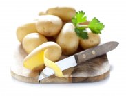 Patatas sobre tabla de cortar - foto de stock
